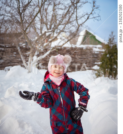 Smiling girl winter clothes holding large snowball standing in deep snow near house wooden fence 138202380