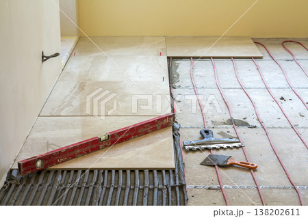 Close-up of lever on ceramic tiles on cement floor. Tiles installation, tools and home improvement, renovation and construction, comfortable modern home concept. Close-up of lever on ceramic tiles on cement floor. Tiles installation, tools and home improvement, renovation and construction, comfortable modern home concept. 138202611