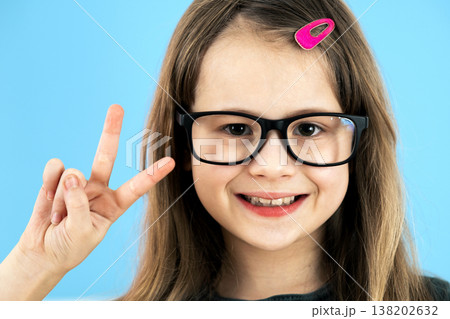 Close up portrait of a child school girl wearing looking glasses isolated on blue background. 138202632
