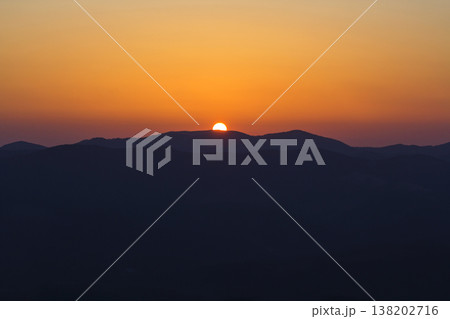 Beautiful sunset in mountains. Wide panorama view of big bright white sun in dramatic orange sky over dark mountain range landscape at sunset or sunrise. Beauty of nature concept. Beautiful sunset in mountains. Wide panorama view of big bright white sun in dramatic orange sky over dark mountain range landscape at sunset or sunrise. Beauty of nature concept. 138202716