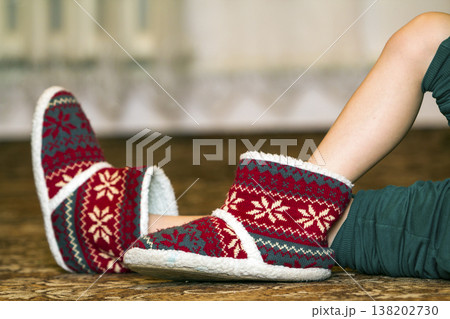 Bare child legs and feet in red winter christmas boots with ornament pattern Bare child legs and feet in red winter christmas boots with ornament pattern 138202730