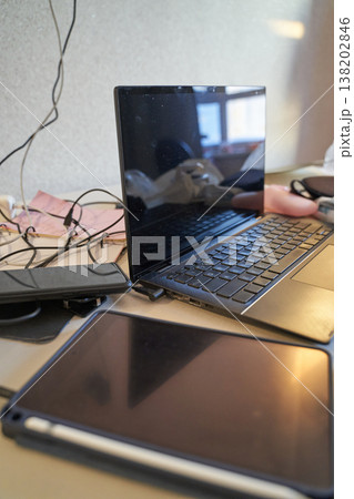 Cluttered Desk With Laptop, Tablet, And Cables Reflect Modern Lifestyle And Tech Dependence Cluttered Desk With Laptop, Tablet, And Cables Reflect Modern Lifestyle And Tech Dependence 138202846