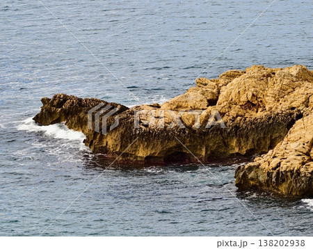Rocky seaside scenery, Serene coastal rocks with sunlight, Peaceful seashore with rugged outcrops and waves 138202938
