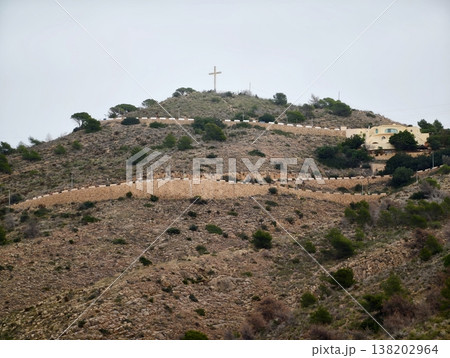 Hilltop hike journey, Tranquil journey up uneven terrain to spiritual landmark under subdued sky Hilltop hike journey, Tranquil journey up uneven terrain to spiritual landmark under subdued sky 138202964