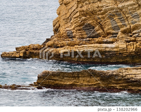 Cliffs meet tranquil ocean background, Vertical stratification of cliffs with serene sea backdrop Cliffs meet tranquil ocean background, Vertical stratification of cliffs with serene sea backdrop 138202966