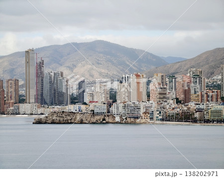 Skyline with mountains, Seaside city skyline featuring tall buildings and cloudy mountain backdrop Skyline with mountains, Seaside city skyline featuring tall buildings and cloudy mountain backdrop 138202971