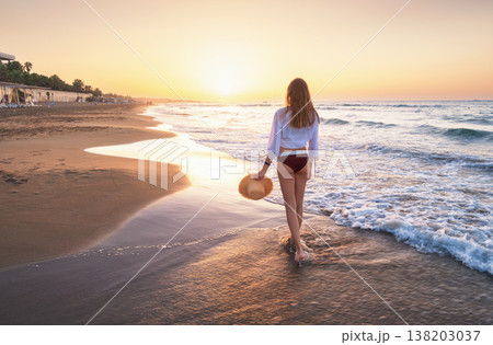 Beautiful young woman with straw hat on the sea with waves Beautiful young woman with straw hat on the sea with waves 138203037