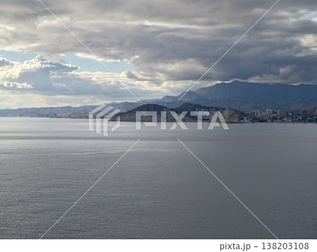 Foreboding storm clouds assemble over quiet coastal village against rugged mountain scenery Foreboding storm clouds assemble over quiet coastal village against rugged mountain scenery 138203108