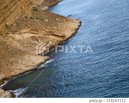 Soft light highlights layered rocky coast, Rhythmic waves and textured cliffs under gentle light 138203112