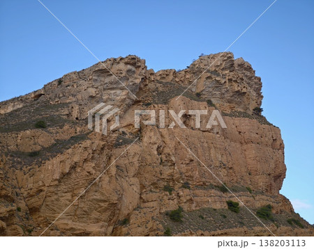 Skyward rock face with shadows, Imposing rocky precipice against azure sky with shadows and sunlight 138203113
