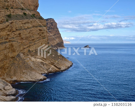 Gentle hills meeting tranquil ocean view, Sunshine bathes rocky coast with distant island scene 138203116