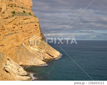 Detailed geological cliff features illuminated by warm sunlight above calming ocean landscapes Detailed geological cliff features illuminated by warm sunlight above calming ocean landscapes 138203121