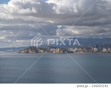 Dramatic atmospheric imagery with soaring clouds over coastal cityscape and vibrant shadows Dramatic atmospheric imagery with soaring clouds over coastal cityscape and vibrant shadows 138203142