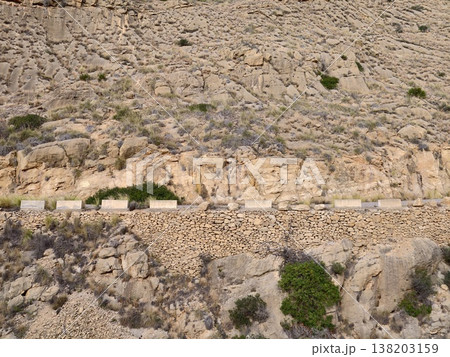 Tranquil seaside trail along rugged cliff with historical stone shelter and natural surroundings 138203159