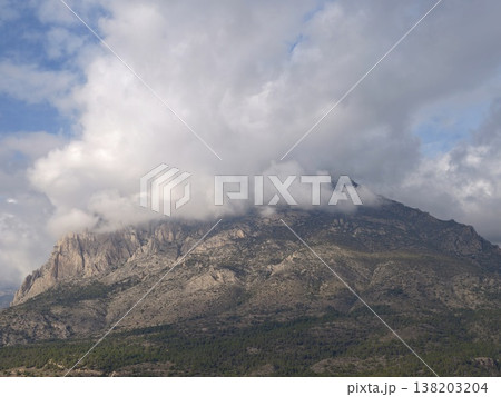 Breathtaking aerial perspective of rugged limestone slopes beneath billowing clouds and vibrant sky 138203204