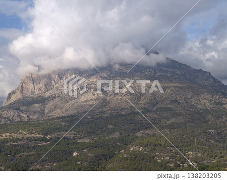 Majestic mountain scene, Vast mountain summit surrounded by swirling low clouds and dense forest 138203205