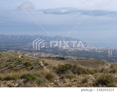 Distant cityscape through natural surroundings, Hillside framing with city skyscrapers on coast Distant cityscape through natural surroundings, Hillside framing with city skyscrapers on coast 138203223