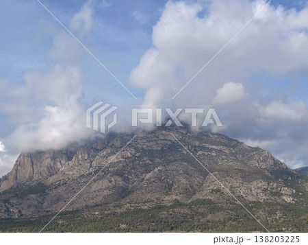 Mystic peaks with billowing clouds, Cloudcovered mountain with rugged terrain and atmospheric tension Mystic peaks with billowing clouds, Cloudcovered mountain with rugged terrain and atmospheric tension 138203225