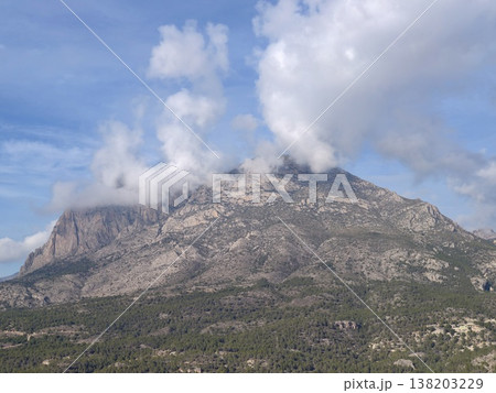 Rugged mountain summit under swirling weather, Dramatic rocky mountain peak shrouded in mist and shadows Rugged mountain summit under swirling weather, Dramatic rocky mountain peak shrouded in mist and shadows 138203229
