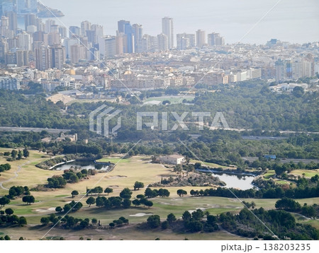 Lush golf course and tranquil lakes in front of bustling city skyline under radiant sunlight 138203235
