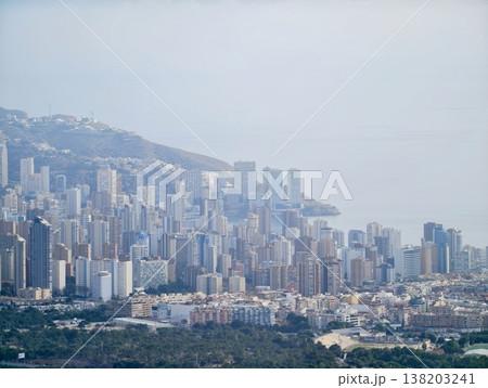 Vertical structures at shoreline merge with misty hills and rocky terrain creating layered scenic composition Vertical structures at shoreline merge with misty hills and rocky terrain creating layered scenic composition 138203241