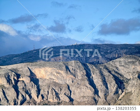 Illuminated cliffside exposing complex stratification and rugged terrain ideal for exploration Illuminated cliffside exposing complex stratification and rugged terrain ideal for exploration 138203355