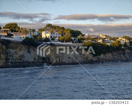 Peaceful cliffs overlook shimmering ocean, Calm shoreline scene with houses and gentle waves 138203413