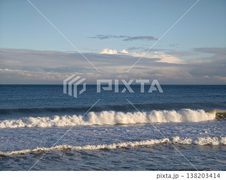 White crests roll over sandy beaches vibrantly, Dynamic ocean waves break with frothy spray by shore 138203414