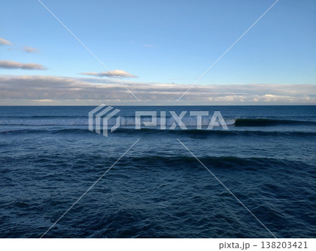 Peaceful blue ocean meeting distant sky, Calm and clear ocean stretches beneath softly cloudy sky Peaceful blue ocean meeting distant sky, Calm and clear ocean stretches beneath softly cloudy sky 138203421