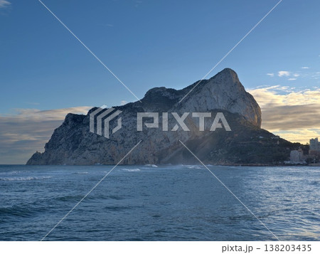 Misty sunset scene of rocky promontory, Solitary sea formation under moody sky and breaking waves Misty sunset scene of rocky promontory, Solitary sea formation under moody sky and breaking waves 138203435