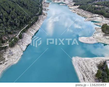 Peaceful lake scene, Serene aerial view of turquoise lake bordered by dense pines and rocky edges 138203457
