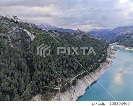 Panoramic aerial image showcasing vivid blue reservoir amid rugged pinecovered slopes and dramatic cliffs Panoramic aerial image showcasing vivid blue reservoir amid rugged pinecovered slopes and dramatic cliffs 138203460