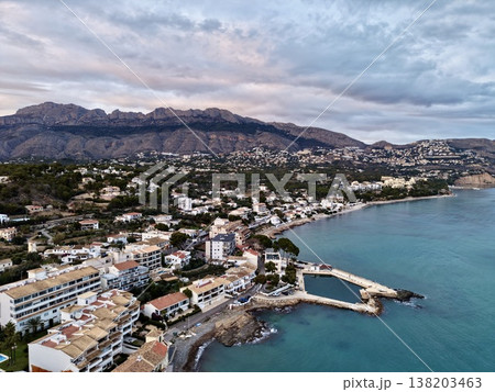 Cloudy harbor with calm surroundings, Overcast shoreline with clustered houses and muted turquoise water 138203463