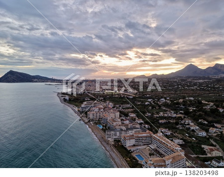 Serene seaside view, Tranquil seaside landscape featuring muted sunset colors and mountain silhouettes 138203498