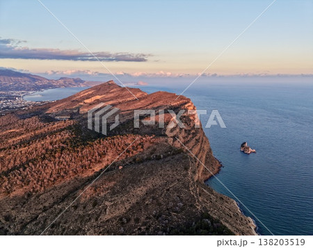 Distant horizon with vibrant light, Scenic headland illuminated by golden sunset over calm sea 138203519