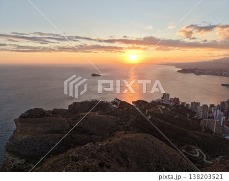 Darkened sea and hills highlighted by glowing coastal and offshore lights under evening sky 138203521