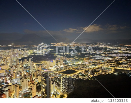 Calm seaside evening with glowing lights, Peaceful coastal walk under illuminated skyline and gentle waves 138203538