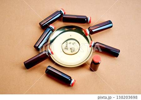 Glass vials surrounding golden plate with serum drops 138203698