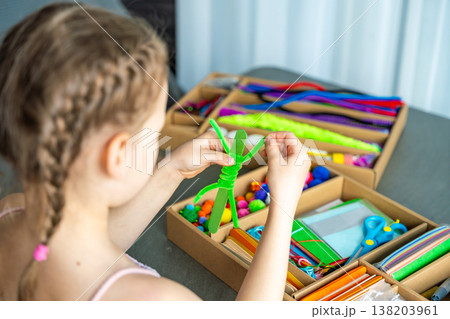 Little girl making craft with colorful materials at table using creative kit at home. Kids creativity development fine motor skills and learning through play concept. Little girl making craft with colorful materials at table using creative kit at home. Kids creativity development fine motor skills and learning through play concept. 138203961