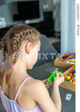 Little girl making craft with colorful materials at table using creative kit at home. Kids creativity development fine motor skills and learning through play concept. Little girl making craft with colorful materials at table using creative kit at home. Kids creativity development fine motor skills and learning through play concept. 138203963