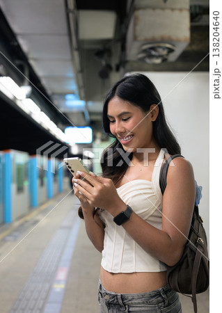 Thai Woman Using Smartphone at Hong Kong Subway Station Platform 138204640