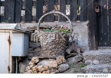 Decorative Stone Basket Planter with Flowers near Rustic Fence 138205587