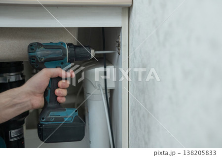 The technician removes the door from the kitchen cabinet. 138205833