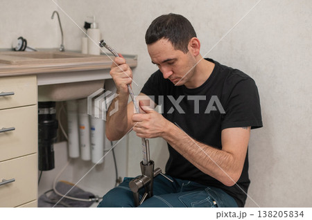 A plumber is replacing a faucet in the kitchen. 138205834
