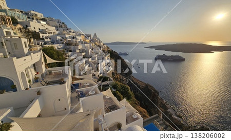 Sunset view over Santorini whitewashed cliffside overlooking the caldera with cruise ships below. 138206002