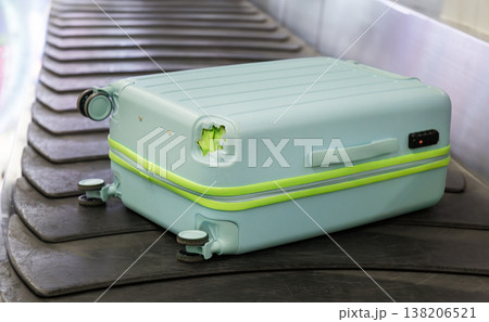 Damaged hard shell suitcase with hole and visible interior on baggage conveyor belt airport close up view. Damaged hard shell suitcase with hole and visible interior on baggage conveyor belt airport close up view. 138206521