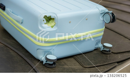 Damaged hard shell suitcase with hole and visible interior on baggage conveyor belt airport close up view. Damaged hard shell suitcase with hole and visible interior on baggage conveyor belt airport close up view. 138206525
