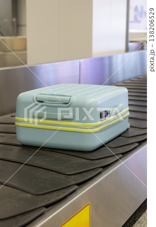 Light blue suitcase moving on airport baggage carousel with metal conveyor system terminal interior. Light blue suitcase moving on airport baggage carousel with metal conveyor system terminal interior. 138206529