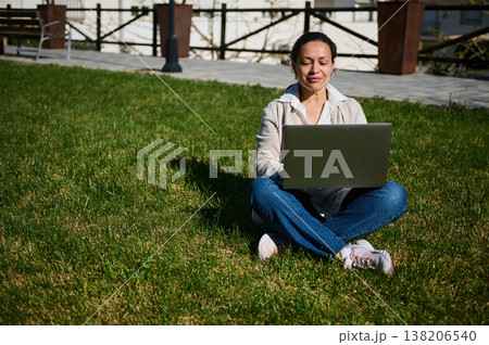 Woman Using Laptop Outdoors Sitting on Grass Remote Work Studying Relaxed in Sunny Park Woman Using Laptop Outdoors Sitting on Grass Remote Work Studying Relaxed in Sunny Park 138206540