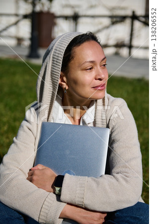 Woman Holding Laptop Outdoors Relaxing in Park Hoodie Remote Work Student Studying Technology Woman Holding Laptop Outdoors Relaxing in Park Hoodie Remote Work Student Studying Technology 138206552